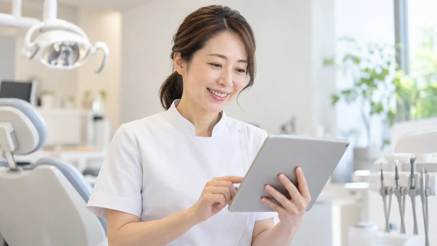 タブレットを見て笑顔になる歯科医師のイメージ写真